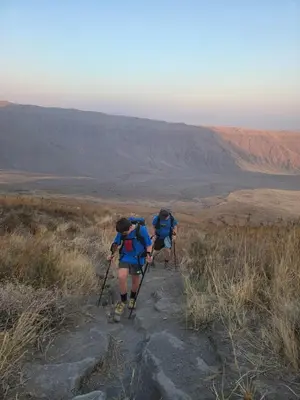 two people hiking on a trail in the desert at Lengai Maasai homestay in Mtowabaga