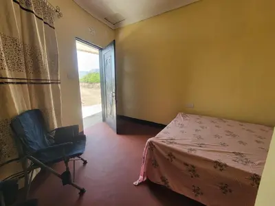 a room with a bed and a chair and a window at Lengai Maasai homestay in Mtowabaga