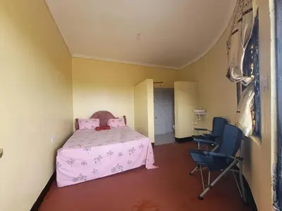 a bedroom with a pink bed and a chair at Lengai Maasai homestay in Mtowabaga
