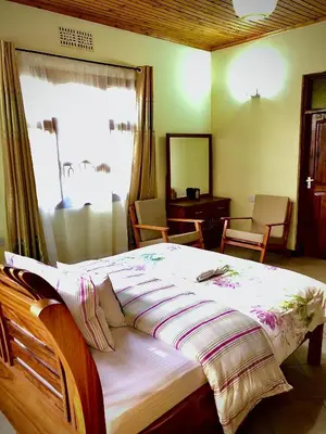 a bedroom with a bed with a window and a desk at Kibebe ataraxia house in Arusha