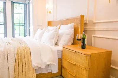 a bed with white pillows and a bottle of wine on a table at Rabi Residence - Two French units sleeps 4 in Arusha