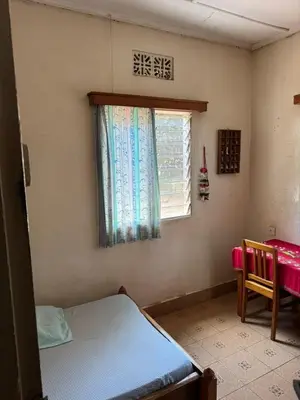 a small bedroom with a bed and a window at Kwetu Homestay Spacious 4BR Home in Moshi