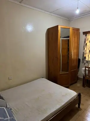 a bedroom with a bed and a wooden cabinet at Kwetu Homestay Spacious 4BR Home in Moshi