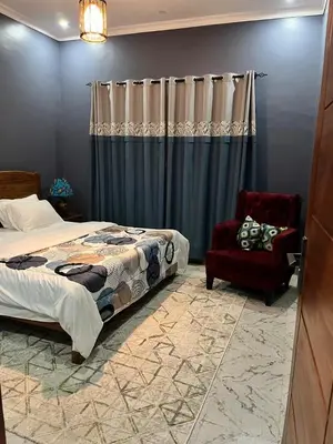 a bedroom with a bed and a chair at Molly's Cozy Place in Arusha