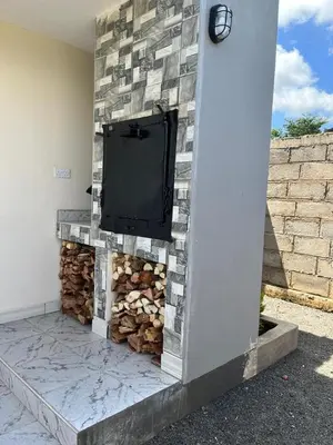 a fireplace with a tv on a stone wall at Molly's Cozy Place in Arusha