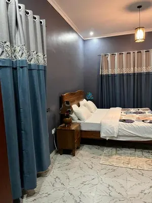a bedroom with a bed with blue curtains at Molly's Cozy Place in Arusha
