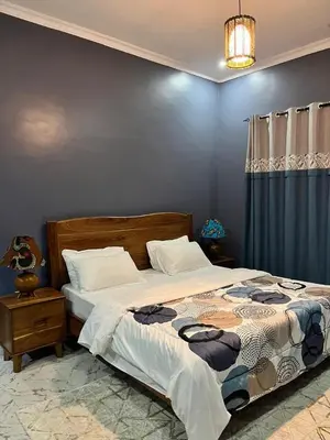 a bedroom with a bed and a blue wall at Molly's Cozy Place in Arusha