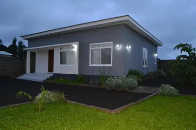 a small house with a green lawn in front of it at Molly's Cozy Place in Arusha