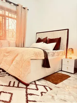 a bedroom with a large bed and a rug at Cozy-Homey with solar system -Firepit- Free Parking-Gardenswing in Arusha