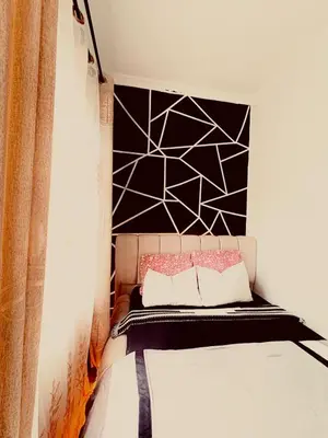 a bedroom with a bed with a black and white wall at Cozy-Homey with solar system -Firepit- Free Parking-Gardenswing in Arusha