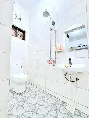 a white bathroom with a toilet and a sink at Cozy-Homey with solar system -Firepit- Free Parking-Gardenswing in Arusha