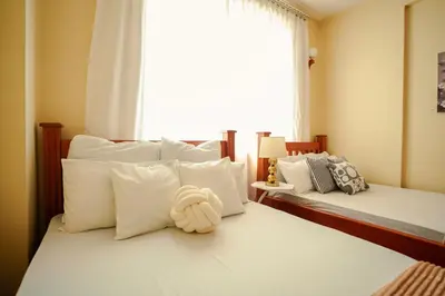 a bedroom with two beds with white pillows and a window at Cozy Urban home in Arusha