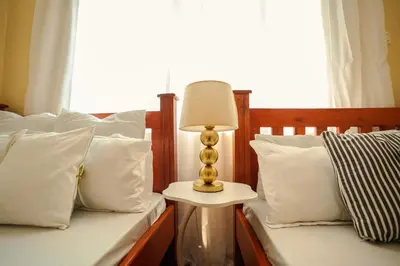 a bedroom with two beds and a lamp on a side table at Cozy Urban home in Arusha