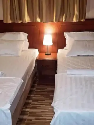 two beds in a room with a lamp on a table at River point inn in Arusha