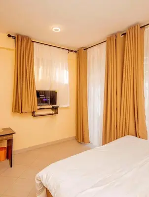 a bedroom with a bed and a window with curtains at River point inn in Arusha