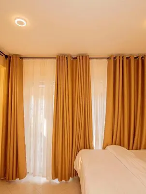 a bedroom with orange curtains and a bed at River point inn in Arusha
