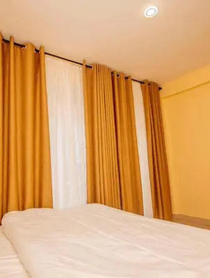 a bed in a bedroom with orange curtains at River point inn in Arusha