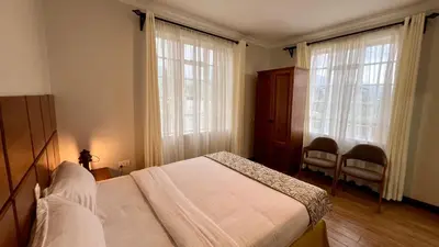 a bedroom with a bed and two large windows at Iwandaa Apartments in Nkoanrua