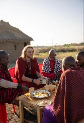 a group of people sitting around a table eating food at Ewang'ani Maasai Cultural Village - Overnight Experience and Tour in Sanya Chini Station