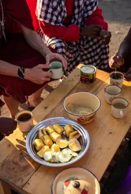 a group of people standing around a table with a plate of food at Ewang'ani Maasai Cultural Village - Overnight Experience and Tour in Sanya Chini Station