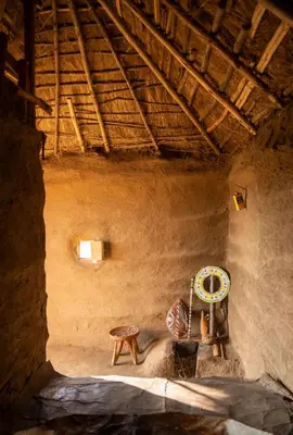 a room with a table and a stool in a building at Ewang'ani Maasai Cultural Village - Overnight Experience and Tour in Sanya Chini Station