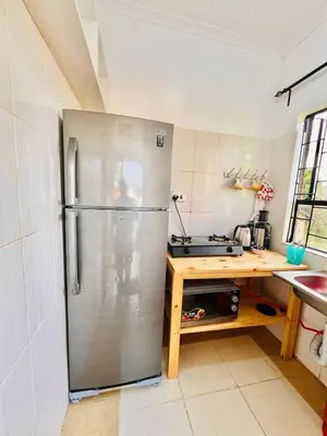 a kitchen with a stainless steel refrigerator and a table at Oshey Home Stay in Arusha