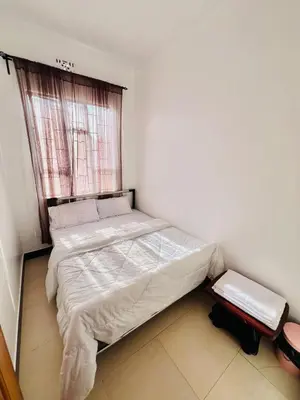 a small bedroom with a bed with a window at Oshey Home Stay in Arusha