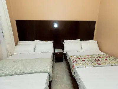 two beds in a hotel room with white sheets and pillows at Msafiri Haven in Moshi