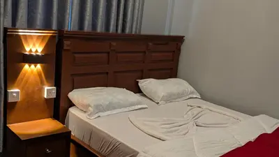 a bed with a wooden headboard next to a lamp at AvocadoAirbnb in Arusha