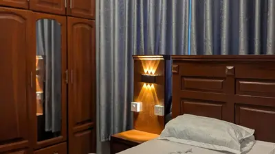 a bedroom with a bed and a lamp next to a curtain at AvocadoAirbnb in Arusha