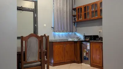 a kitchen with wooden cabinets and a refrigerator at AvocadoAirbnb in Arusha