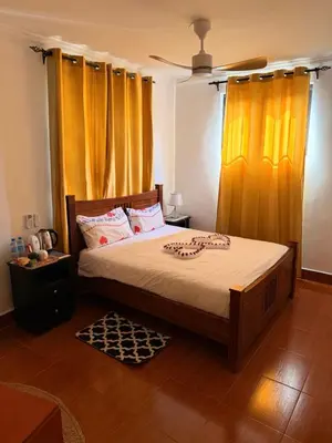 a bedroom with a large bed with orange curtains at Royal Afrika Safari in Arusha