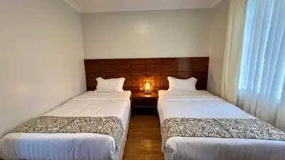 two beds in a small room with a lamp between them at Iwandaa Lodge in Nkoanrua