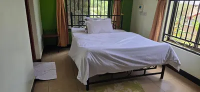 a bed with white sheets and pillows in a room at Greenhome apartment in Poli