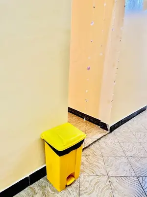 a yellow trash can sitting next to a wall at Cozy 1Bedroom Stand Alone -Near Clock Tower Arusha in Arusha