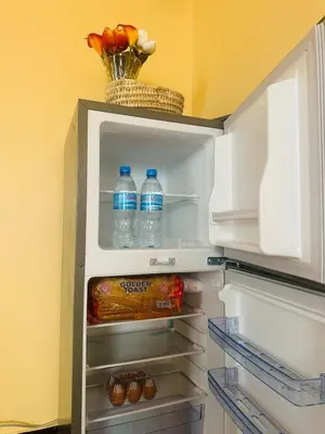 an open refrigerator with bottles of water and food at Cozy 1Bedroom Stand Alone -Near Clock Tower Arusha in Arusha