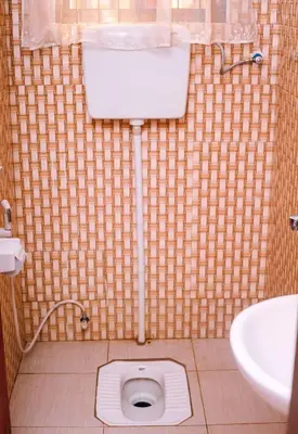 a bathroom with a toilet in a tiled floor at Panamera Safari Lodge in Boma la Ngombe