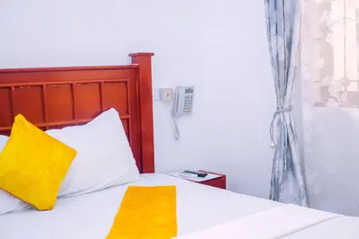 a bedroom with a bed with yellow pillows at Panamera Safari Lodge in Boma la Ngombe