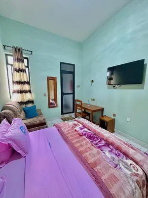 a bedroom with a large purple bed and a tv at Mbogo Safari Hotel in Karatu