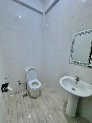 a white bathroom with a toilet and a sink at Mbogo Safari Hotel in Karatu