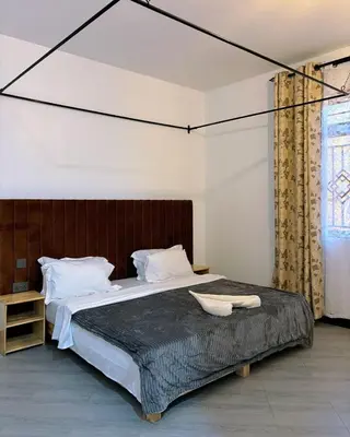 a bedroom with a large bed with a wooden headboard at Araess Homestay Karatu in Karatu