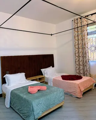 a bedroom with two beds and a window at Araess Homestay Karatu in Karatu