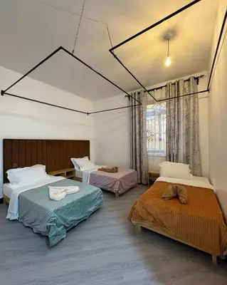a room with three beds and a window at Araess Homestay Karatu in Karatu
