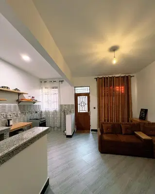 a living room with a couch and a kitchen at Araess Homestay Karatu in Karatu