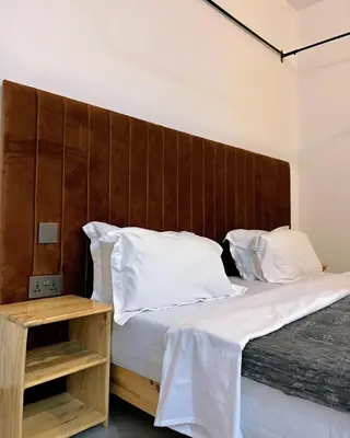a bedroom with a large bed with a wooden headboard at Araess Homestay Karatu in Karatu
