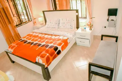 a bedroom with a bed with an orange and white comforter at Kilimanjaro Serenity Lodge & Camp