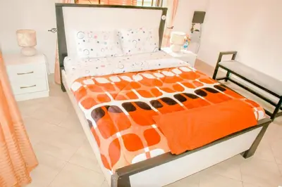 a bed with an orange and white comforter on it at Kilimanjaro Serenity Lodge & Camp