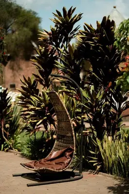 a wicker chair sitting in front of some plants at Explora Lodge in Arusha