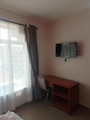 a room with a desk and a television and a window at Atlas Hotel in Arusha