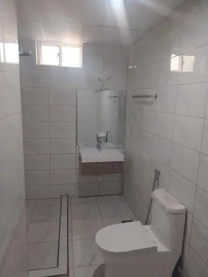 a white bathroom with a toilet and a sink at Atlas Hotel in Arusha